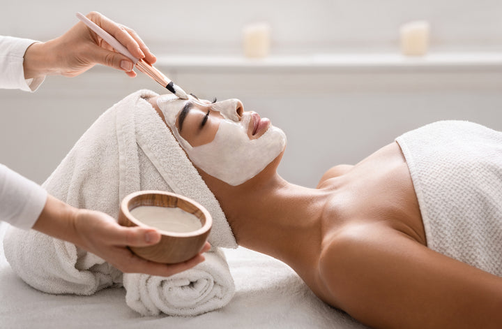 Woman having a mask applied during a facial treatment with towel on