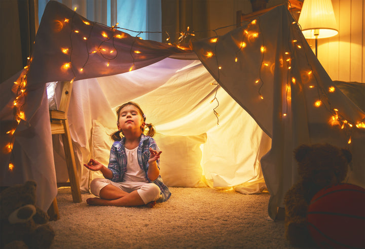 little girl doing yoga in a glowing tent with fairy lights