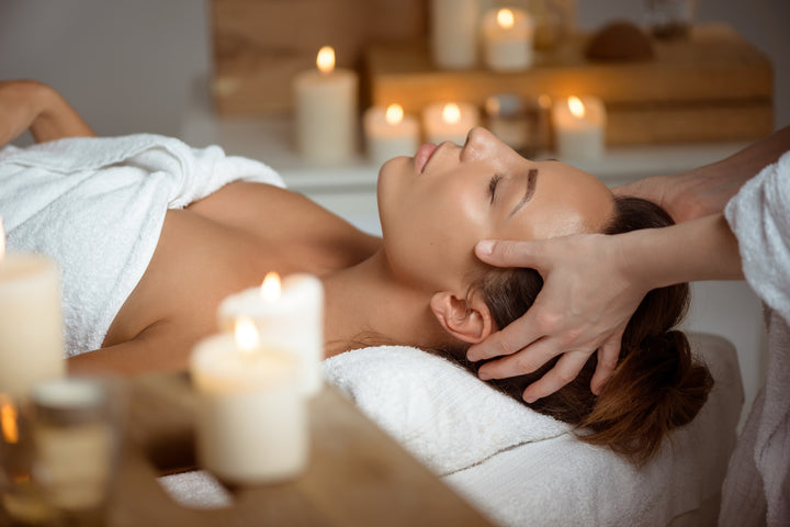 Woman getting a relaxing facial with candles at Pure Beauty & Wellness spa.