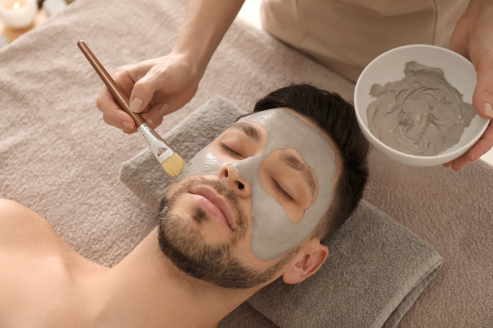 man with facial hair getting a facial and mud mask