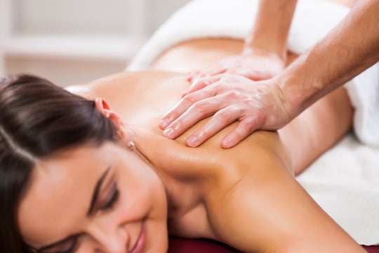 woman with dark hair smiling while getting a back massage