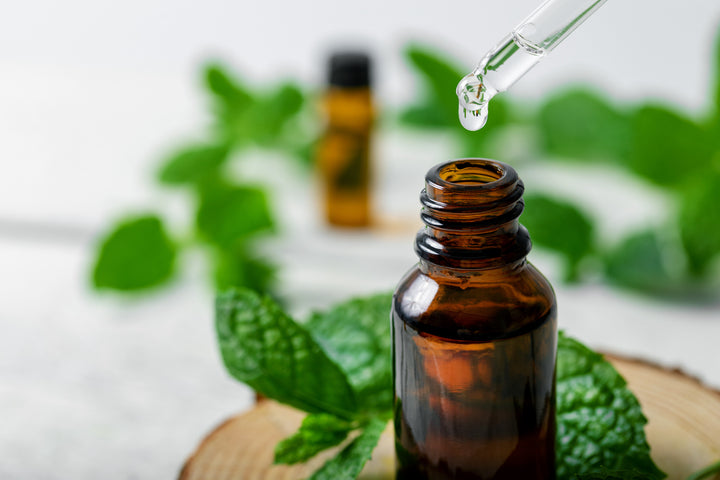 essential oil in brown bottle with dropper and mint