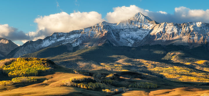 Telluride Colorado's Mount Wilson Range with some snow in the fall with yellow aspen trees.