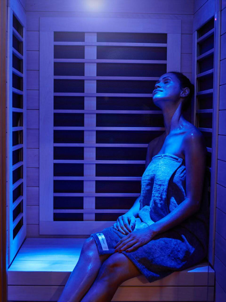 Woman smiling in a far infrared sauna with blue light shining on her