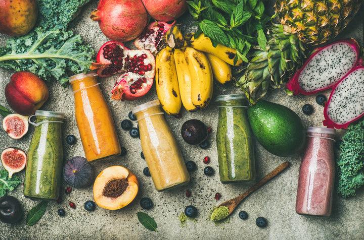 Nectarines, figs, plantains, dragonfruit, pomegranate, pineapple, avocado, blueberries, and juices in glass bottles