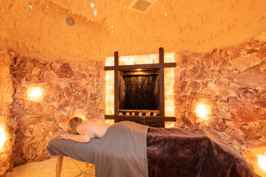 woman with pink salt stones laying on a massage table in a salt cave