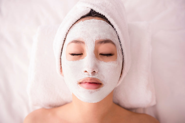 teen girl with towel on her head wearing a face mask with her eyes closed
