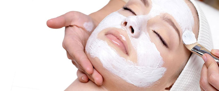 woman getting facial having a white face mask applied