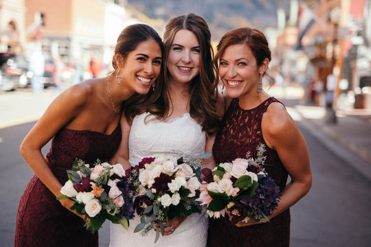 Bride and two bridesmaids holding floral bouquets with profesionaly done make up.